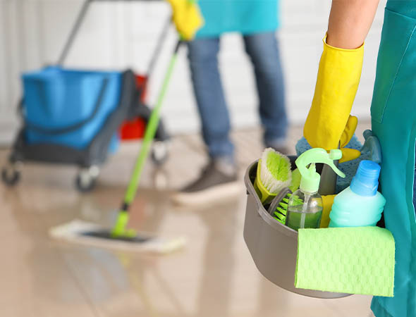 Man and woman mopping the floor of a room. Woman holding cleaning supplies wearing yellow gloves.